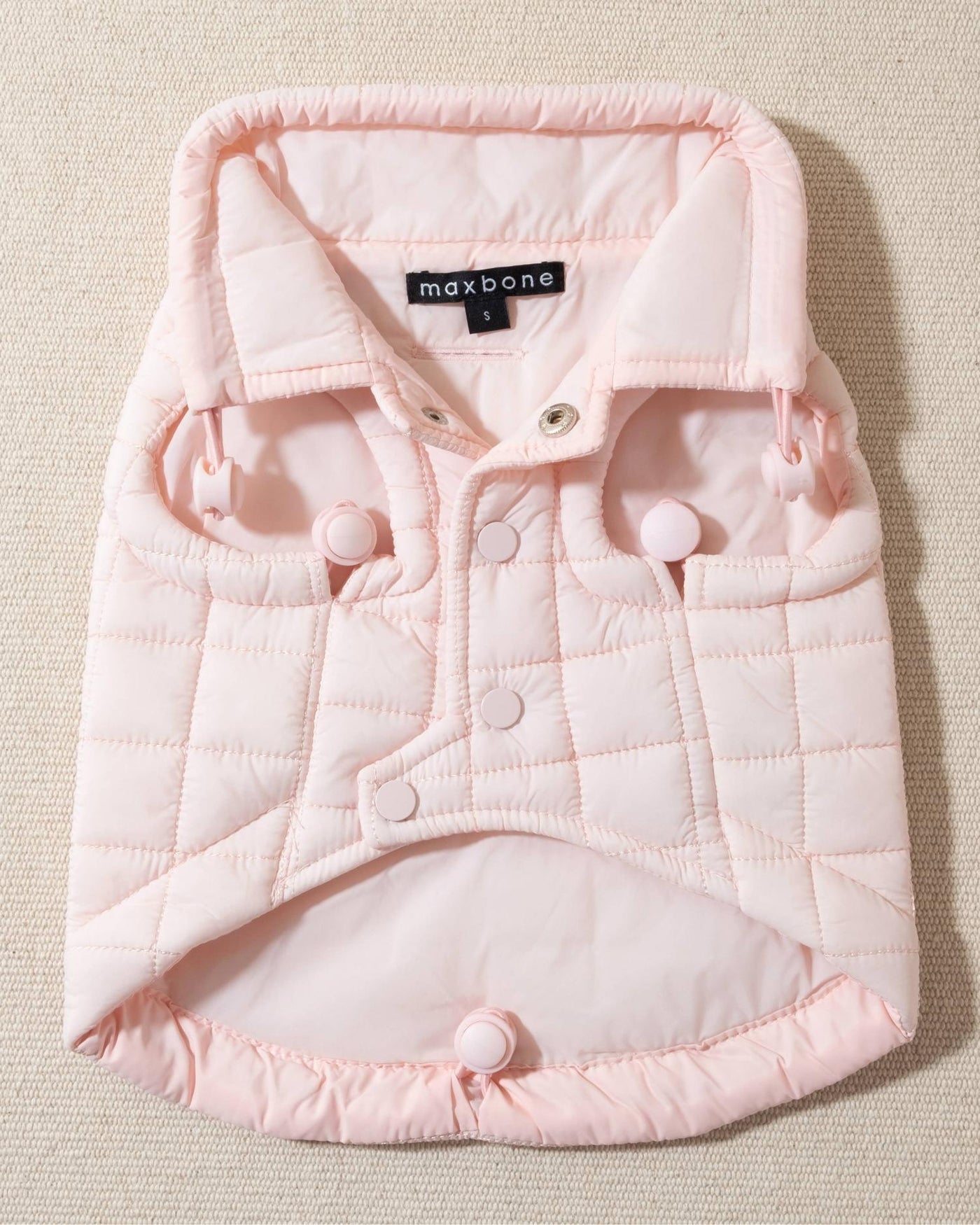 perfect on its own or layered with a cute sweater. This quilted, stylish jacket is fully adjustable, with coordinating light pink cords on the hem, neck, and arm openings. Jacket can be worn over harness, with a small opening for leash attachment on the back. Asymmetrical buttons also make for more secure wear, for even the most portly of pups!. Corgi pink jacket.